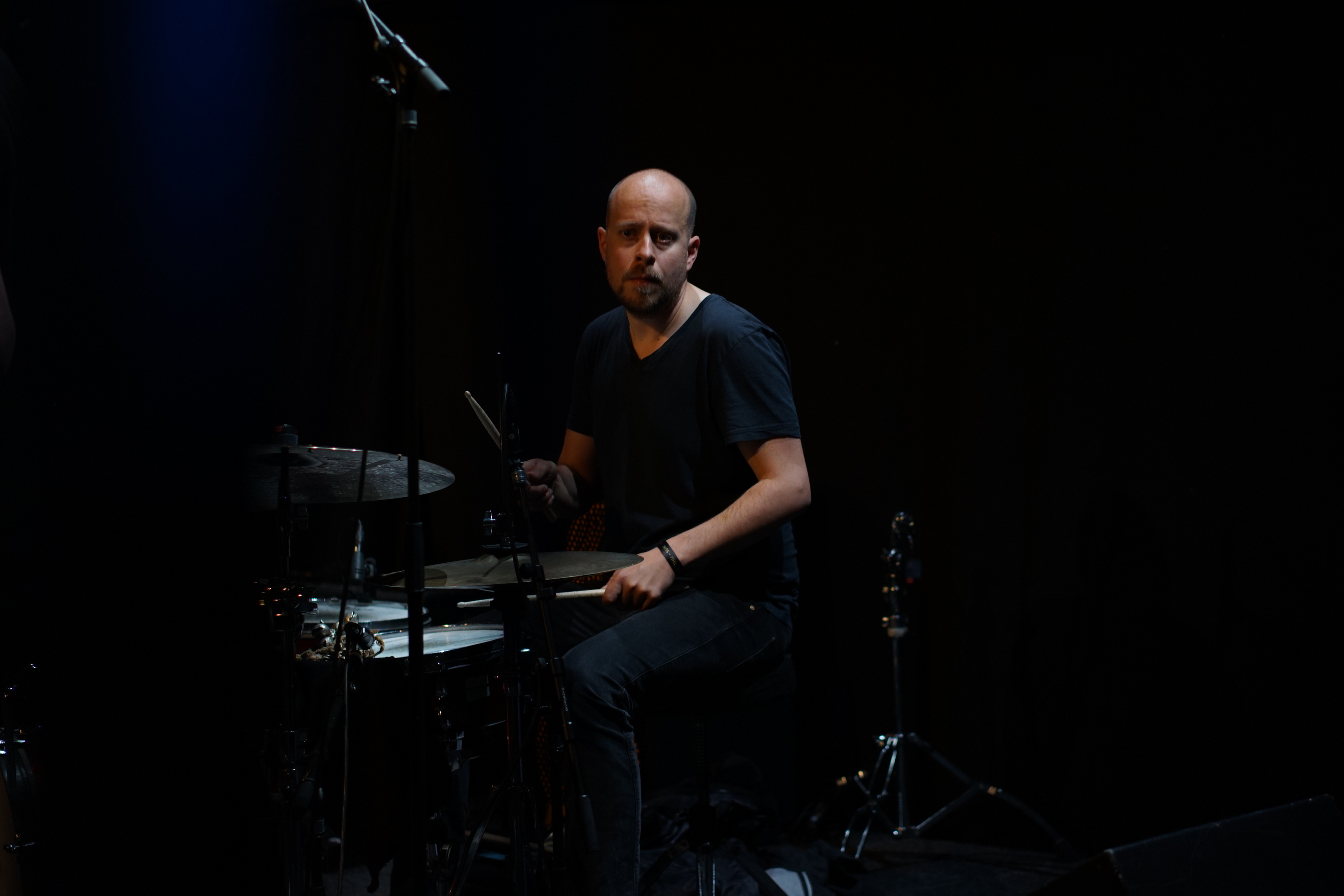 Sebastian Merk seated at a drum kit on a dark stage