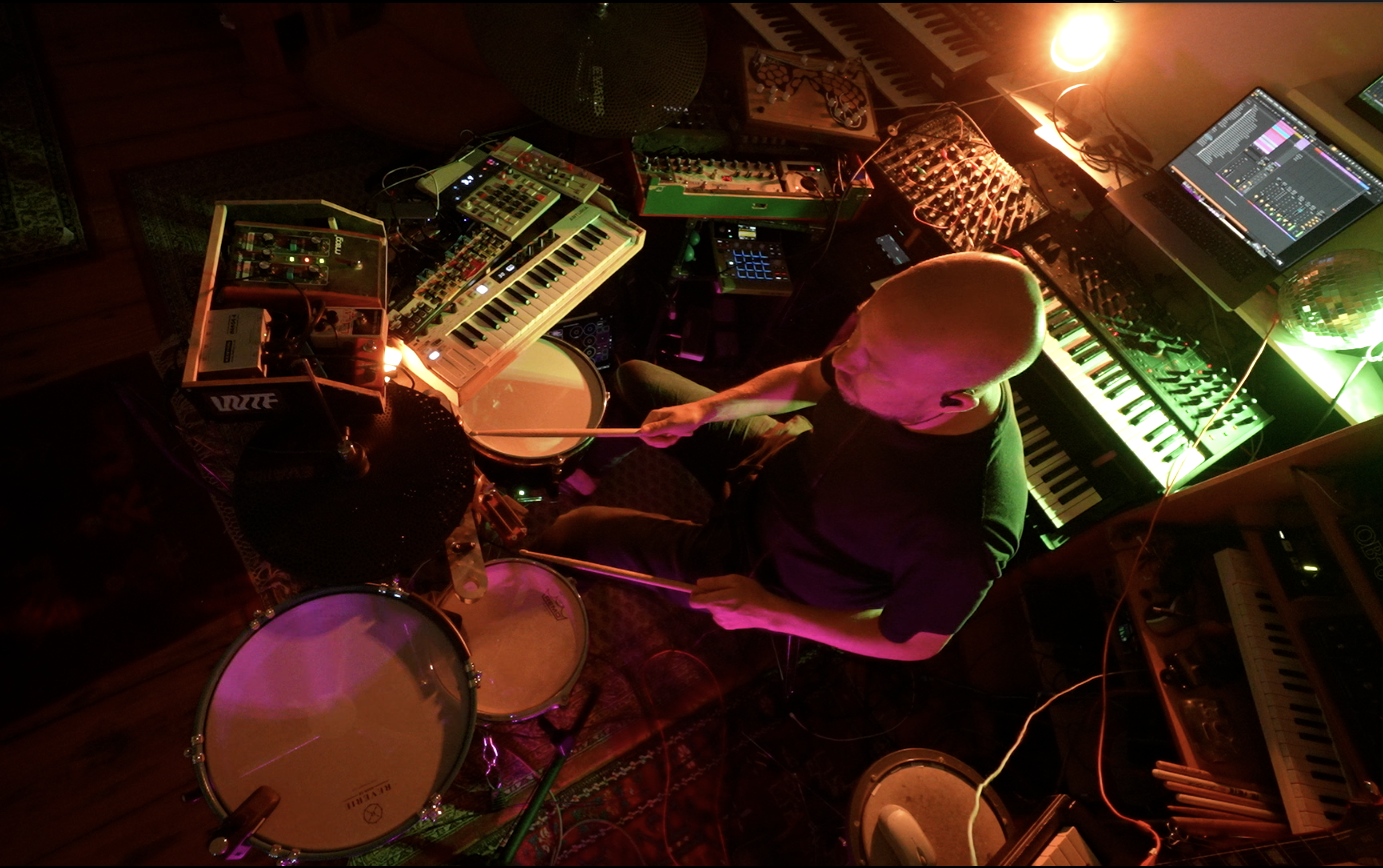 Sebastian Merk at drums and electronic instruments in warm stage lighting